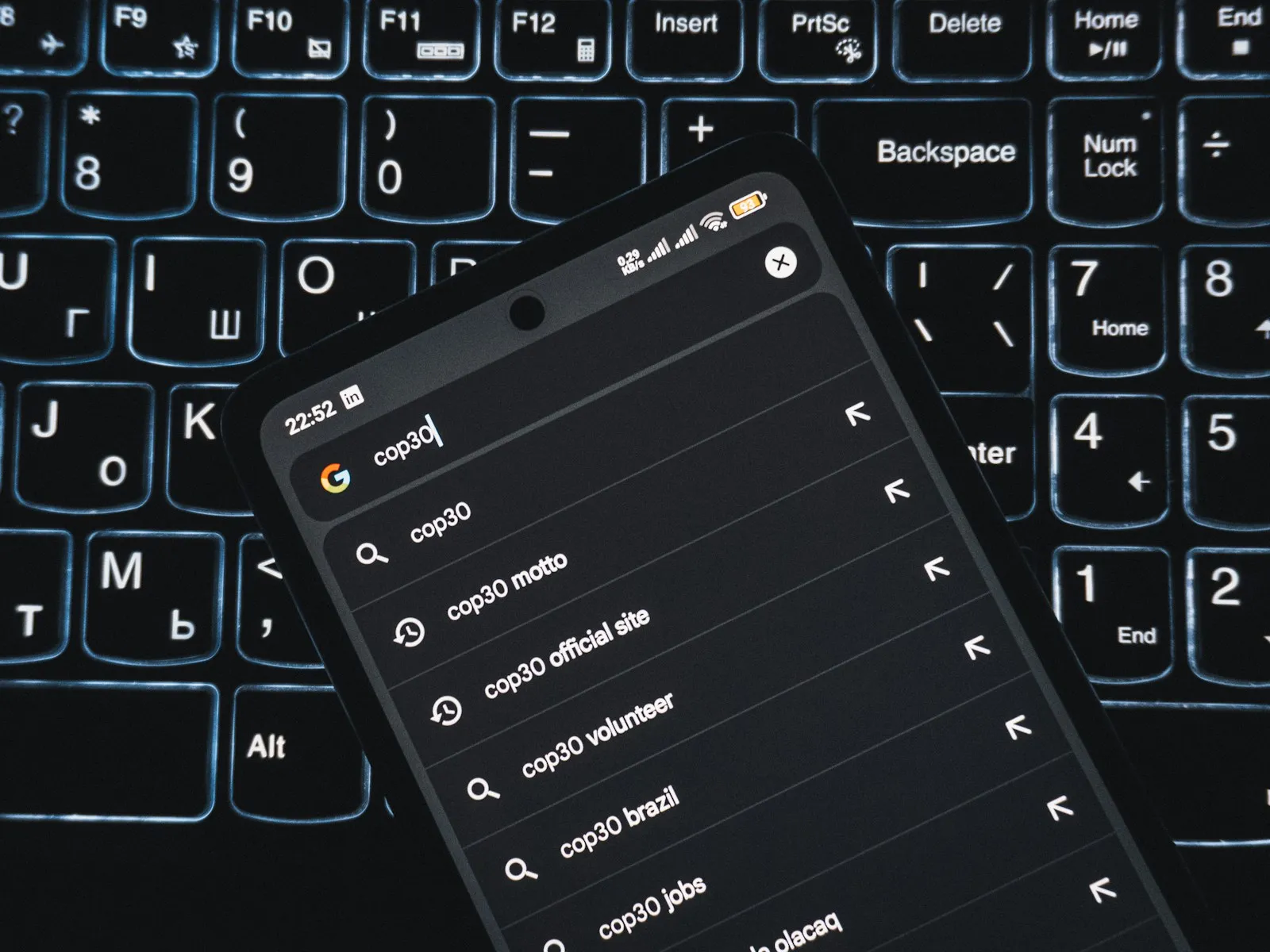 Smartphone mit Google-Suchvorschlägen auf einer beleuchteten Tastatur