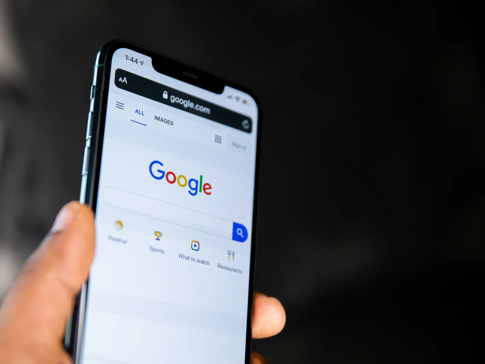 Hand hält ein Smartphone mit geöffneter Google-Suche