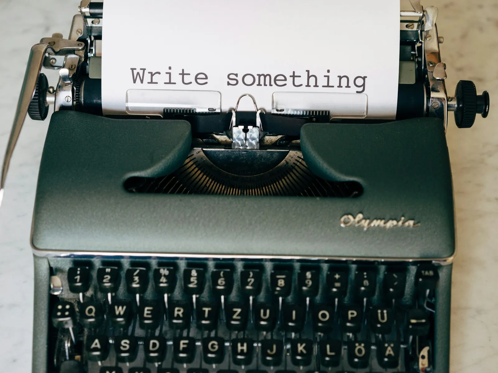 Olympia-Schreibmaschine mit einem Blatt „Write something“